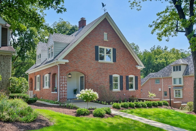 view of front of property with brick siding, a chimney, and a front yard