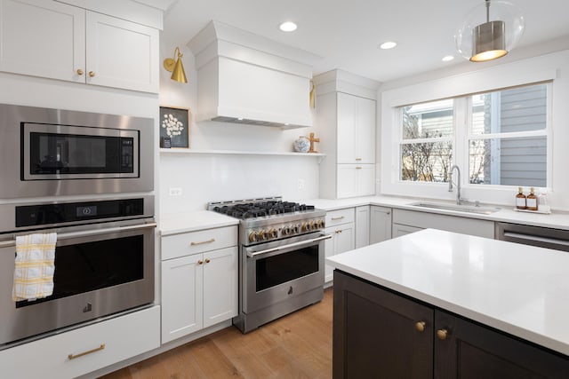 kitchen with a sink, white cabinetry, light countertops, appliances with stainless steel finishes, and light wood-type flooring