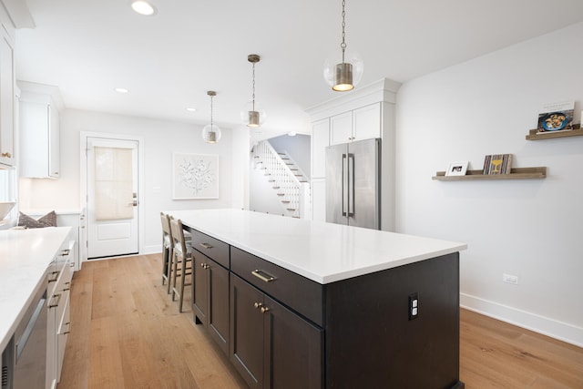 kitchen with light countertops, light wood-type flooring, white cabinets, and high end refrigerator