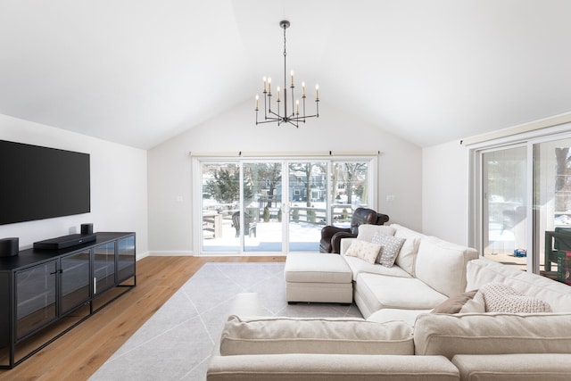 living room featuring lofted ceiling, light wood-style flooring, baseboards, and a notable chandelier