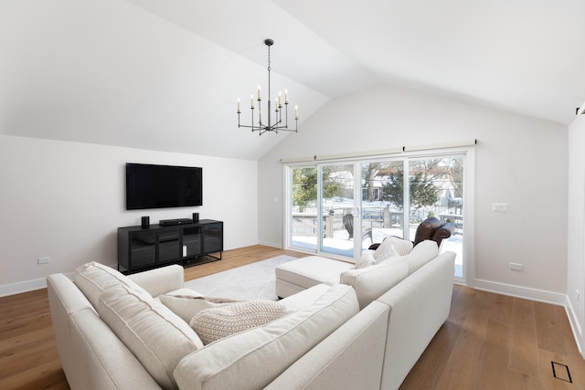 living area featuring baseboards, vaulted ceiling, wood finished floors, and a chandelier