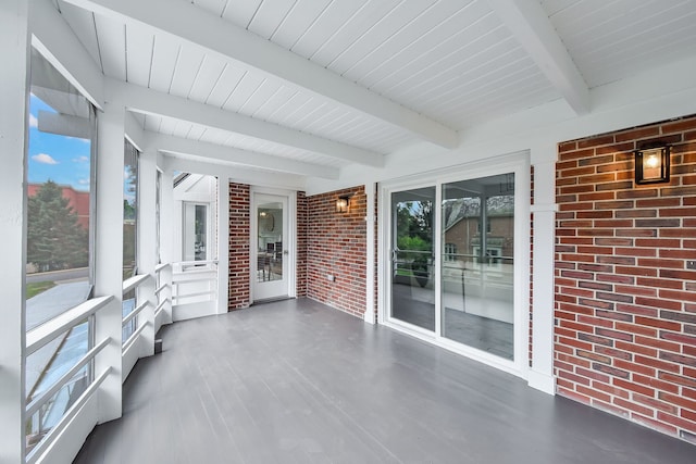 unfurnished sunroom featuring a healthy amount of sunlight and beamed ceiling