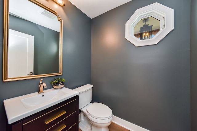 bathroom with baseboards, visible vents, vanity, and toilet