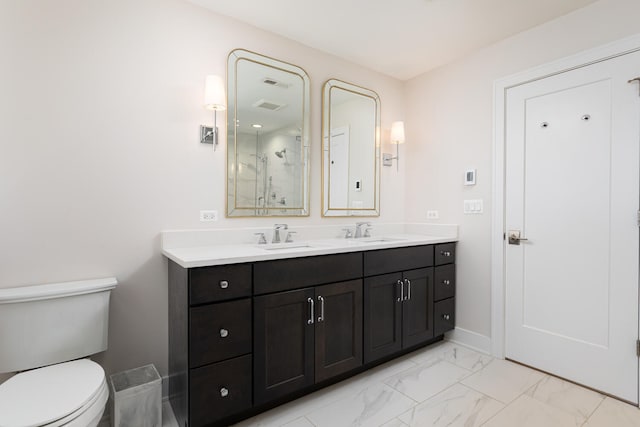 full bath with toilet, marble finish floor, double vanity, and a sink