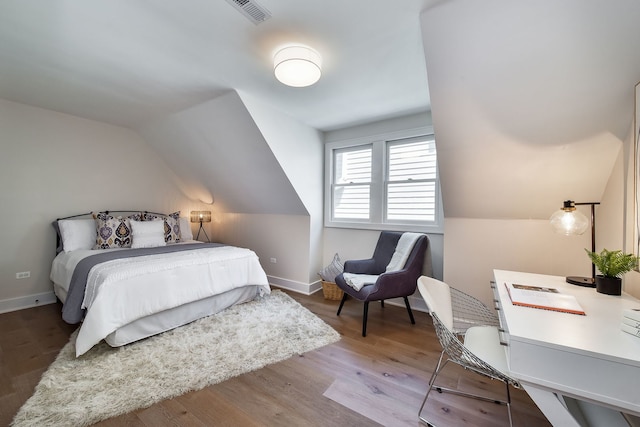 bedroom featuring lofted ceiling, visible vents, baseboards, and wood finished floors