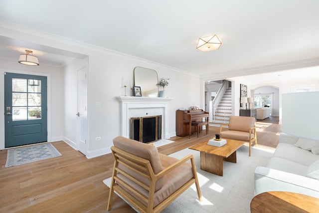 living room featuring a healthy amount of sunlight, a fireplace with flush hearth, stairs, and arched walkways