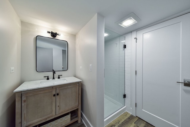 bathroom with wood finished floors, a shower stall, and vanity