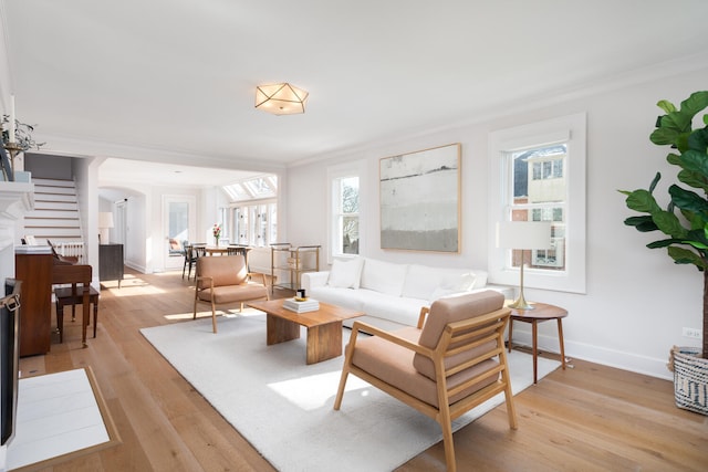 living room featuring arched walkways, stairway, ornamental molding, light wood-type flooring, and baseboards