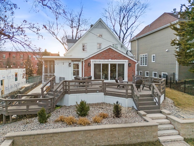 back of house with a deck, brick siding, and fence