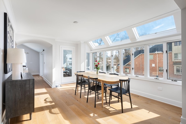 sunroom with lofted ceiling with skylight, arched walkways, and visible vents