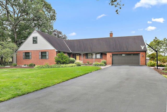 view of front of property featuring aphalt driveway, brick siding, a chimney, an attached garage, and a front yard