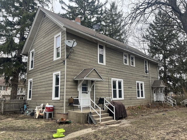 back of property with fence and a chimney