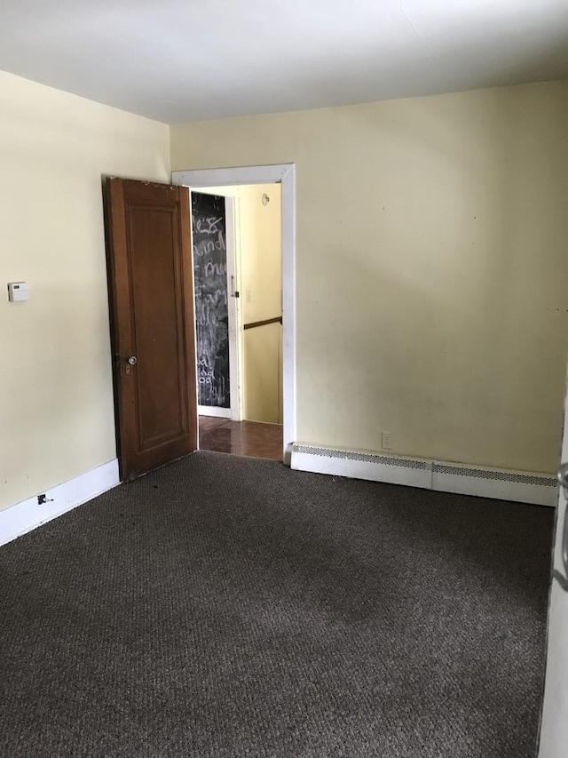 empty room with baseboards and dark colored carpet