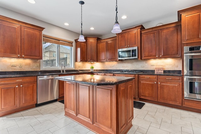 kitchen featuring appliances with stainless steel finishes, pendant lighting, a kitchen island, and tasteful backsplash