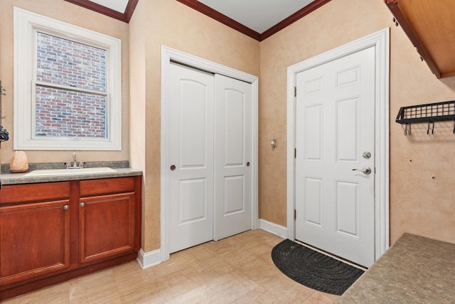 entryway with ornamental molding and baseboards
