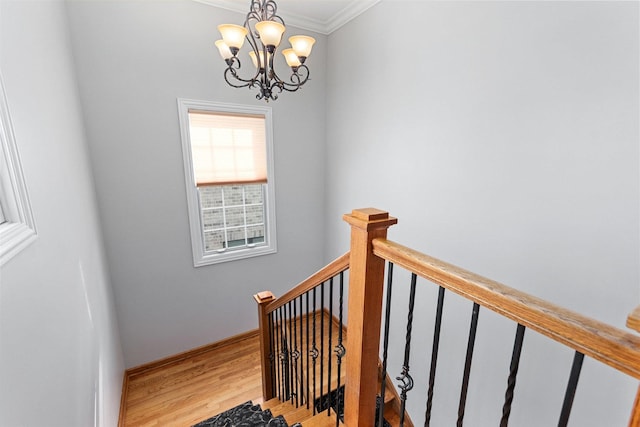 staircase featuring a notable chandelier, baseboards, wood finished floors, and ornamental molding