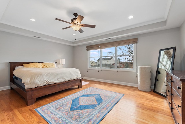 bedroom with visible vents, baseboards, a tray ceiling, light wood-style floors, and recessed lighting