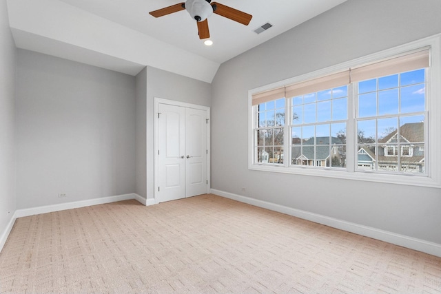unfurnished bedroom with light carpet, visible vents, baseboards, vaulted ceiling, and a closet