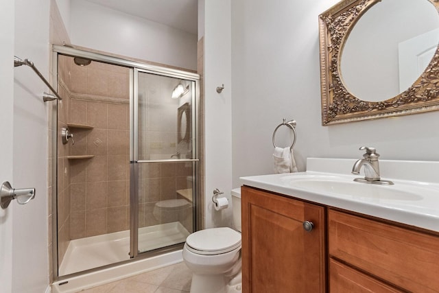 bathroom featuring toilet, a stall shower, vanity, and tile patterned floors
