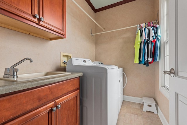 laundry room with washing machine and dryer, a sink, baseboards, cabinet space, and crown molding
