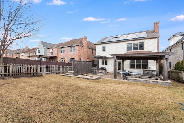 rear view of property featuring a patio area, a fenced backyard, solar panels, and a yard
