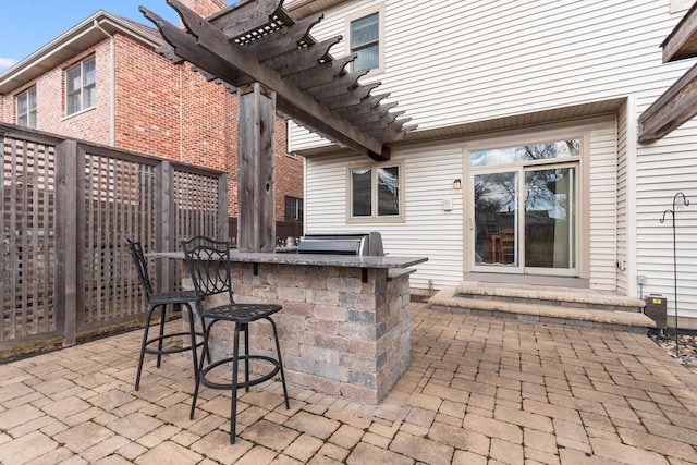 view of patio / terrace featuring exterior kitchen, fence, outdoor dry bar, and a pergola