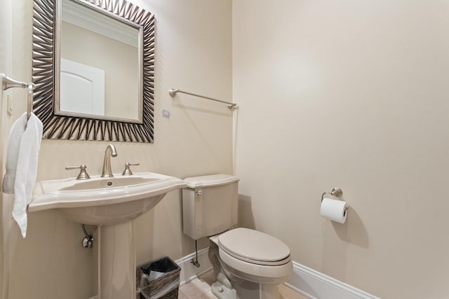 half bathroom with tile patterned floors, toilet, and baseboards