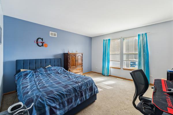 bedroom with carpet floors, visible vents, and baseboards