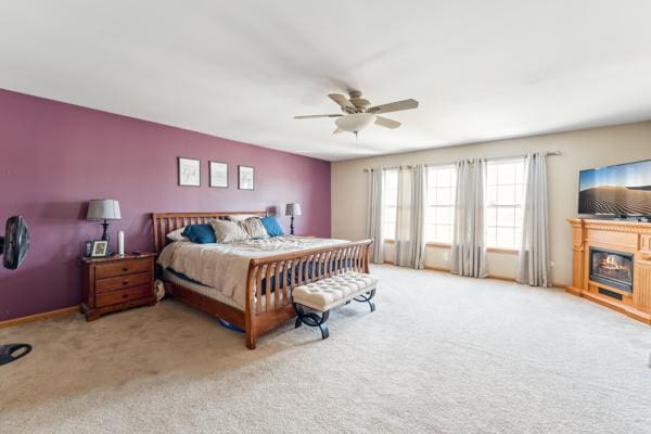 carpeted bedroom featuring a ceiling fan and a glass covered fireplace