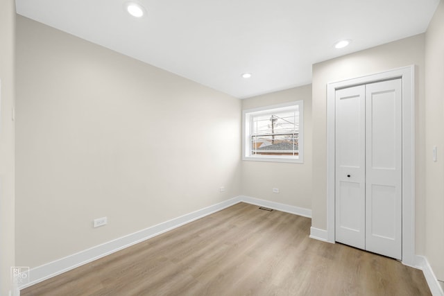 unfurnished bedroom featuring light wood finished floors, recessed lighting, a closet, visible vents, and baseboards