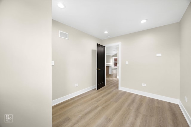 unfurnished room with recessed lighting, light wood-type flooring, visible vents, and baseboards