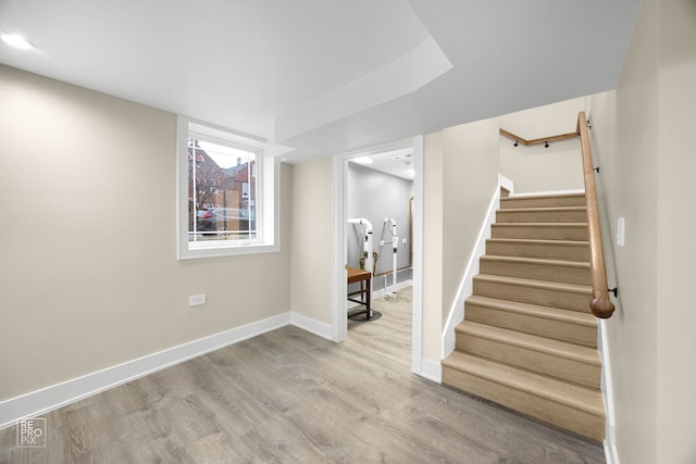 below grade area featuring stairway, baseboards, and wood finished floors