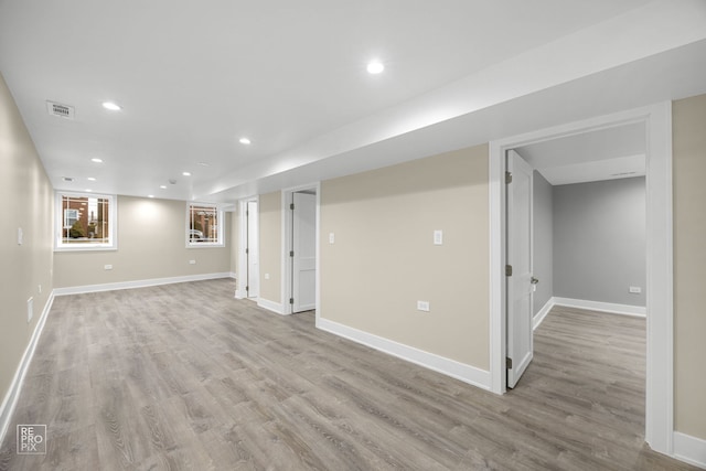 basement featuring light wood-type flooring, baseboards, and visible vents