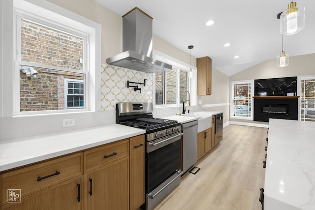 kitchen with hanging light fixtures, appliances with stainless steel finishes, extractor fan, and light wood-type flooring