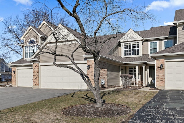 view of front of home featuring brick siding, driveway, and a shingled roof