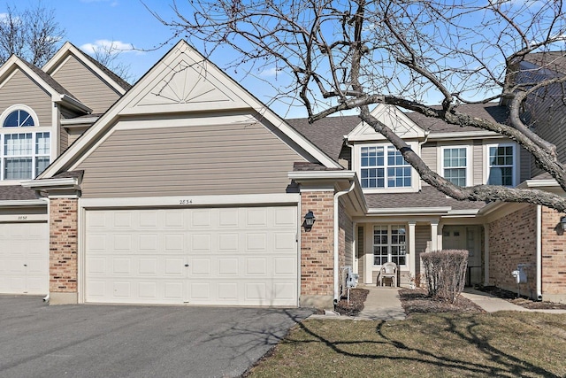 view of front facade featuring an attached garage, brick siding, roof with shingles, and driveway