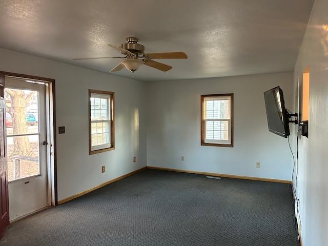 carpeted spare room featuring visible vents, ceiling fan, and baseboards