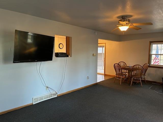 unfurnished dining area with carpet, visible vents, ceiling fan, and baseboards