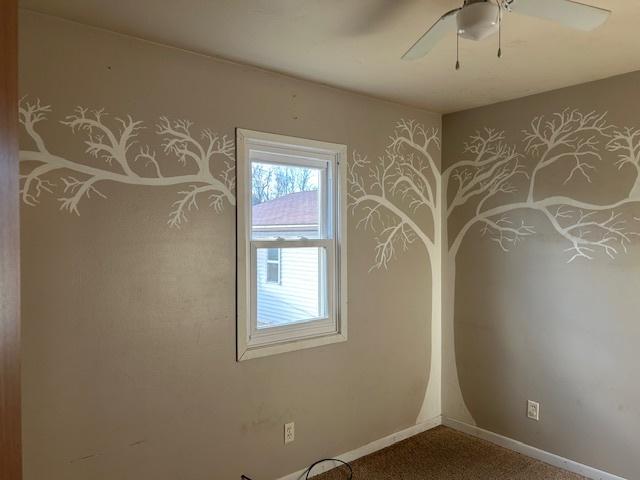 carpeted empty room featuring baseboards and a ceiling fan