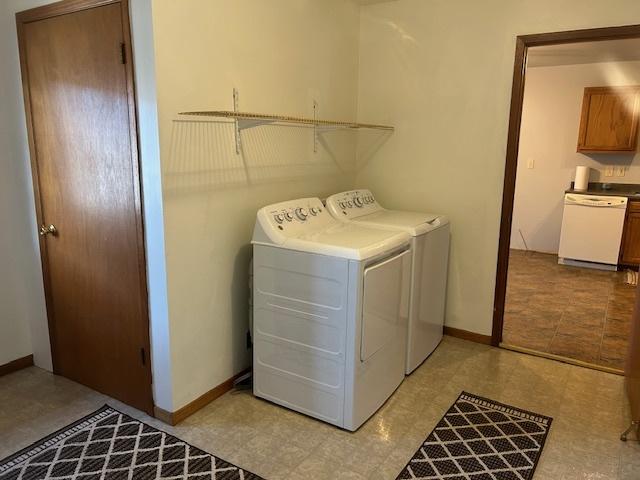 clothes washing area featuring laundry area, baseboards, and washing machine and clothes dryer