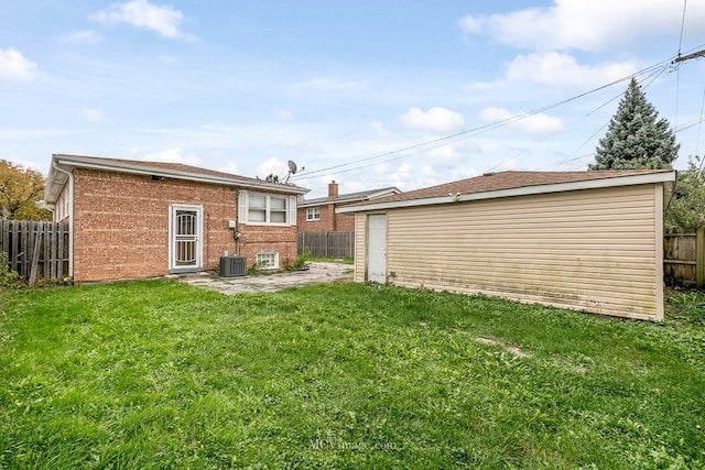 rear view of property featuring an outbuilding, a yard, brick siding, and a fenced backyard