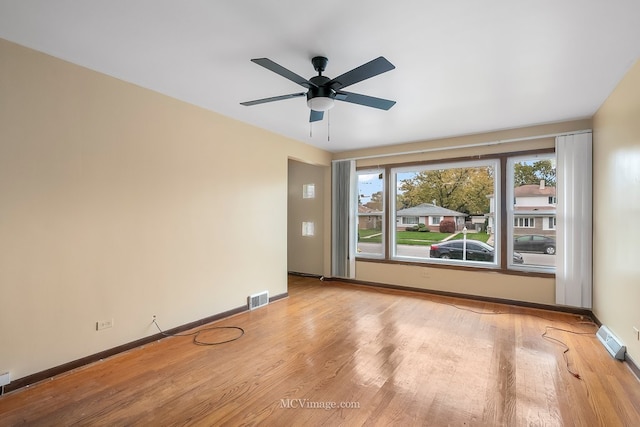 empty room featuring visible vents, baseboards, and wood finished floors