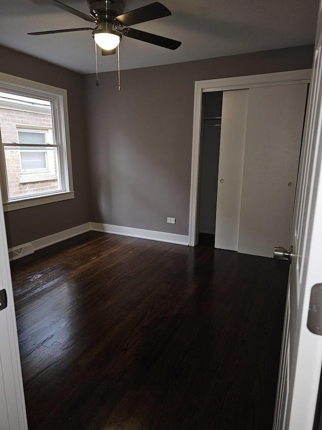 unfurnished bedroom with visible vents, a ceiling fan, baseboards, a closet, and dark wood finished floors