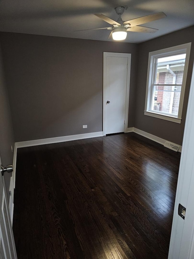 unfurnished room featuring a ceiling fan, baseboards, visible vents, and dark wood-style flooring