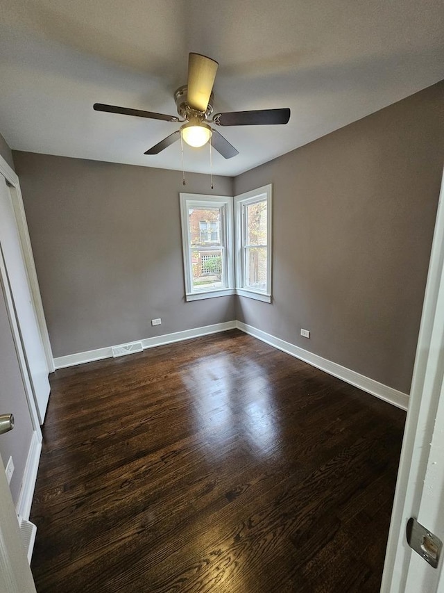 unfurnished bedroom with ceiling fan, dark wood-type flooring, visible vents, and baseboards