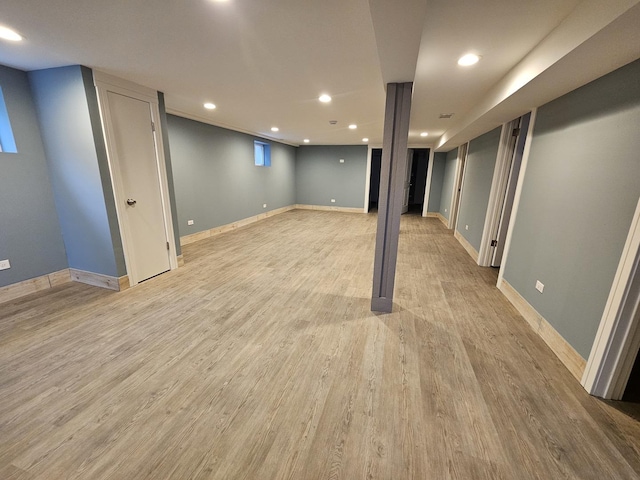 finished below grade area with baseboards, recessed lighting, and light wood-style floors