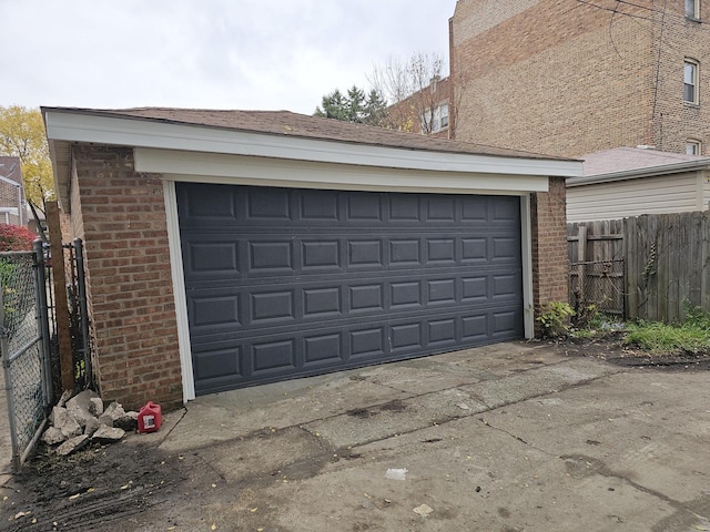 garage with concrete driveway and fence