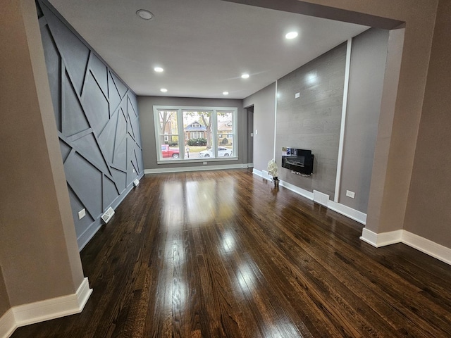 unfurnished living room featuring a tile fireplace, baseboards, dark wood-style flooring, and recessed lighting