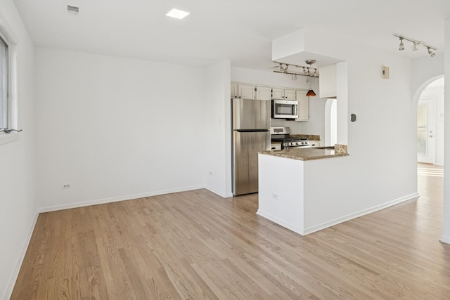 kitchen featuring baseboards, arched walkways, appliances with stainless steel finishes, and light wood finished floors