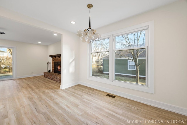 unfurnished living room featuring baseboards, visible vents, light wood-type flooring, a brick fireplace, and recessed lighting